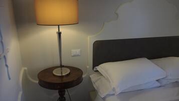 Un lit avec du linge de lit blanc et une table ronde avec une lampe à côté.
