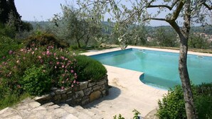 A swimming pool surrounded by stone walls and lush greenery, with a view of distant hills. - I Parigi Corbinelli (Florence)