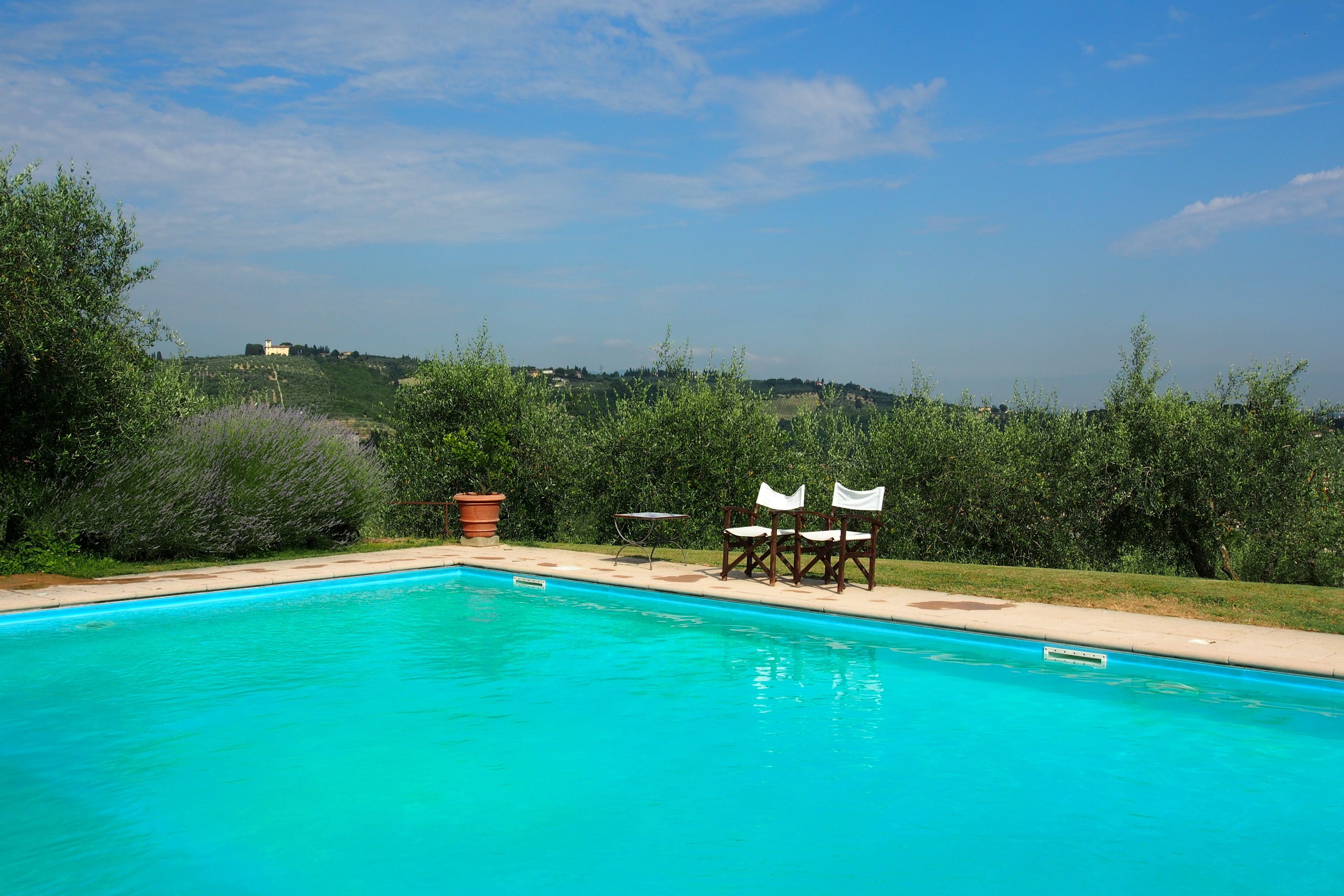 A swimming pool with a view of a hill and a building in the distance.