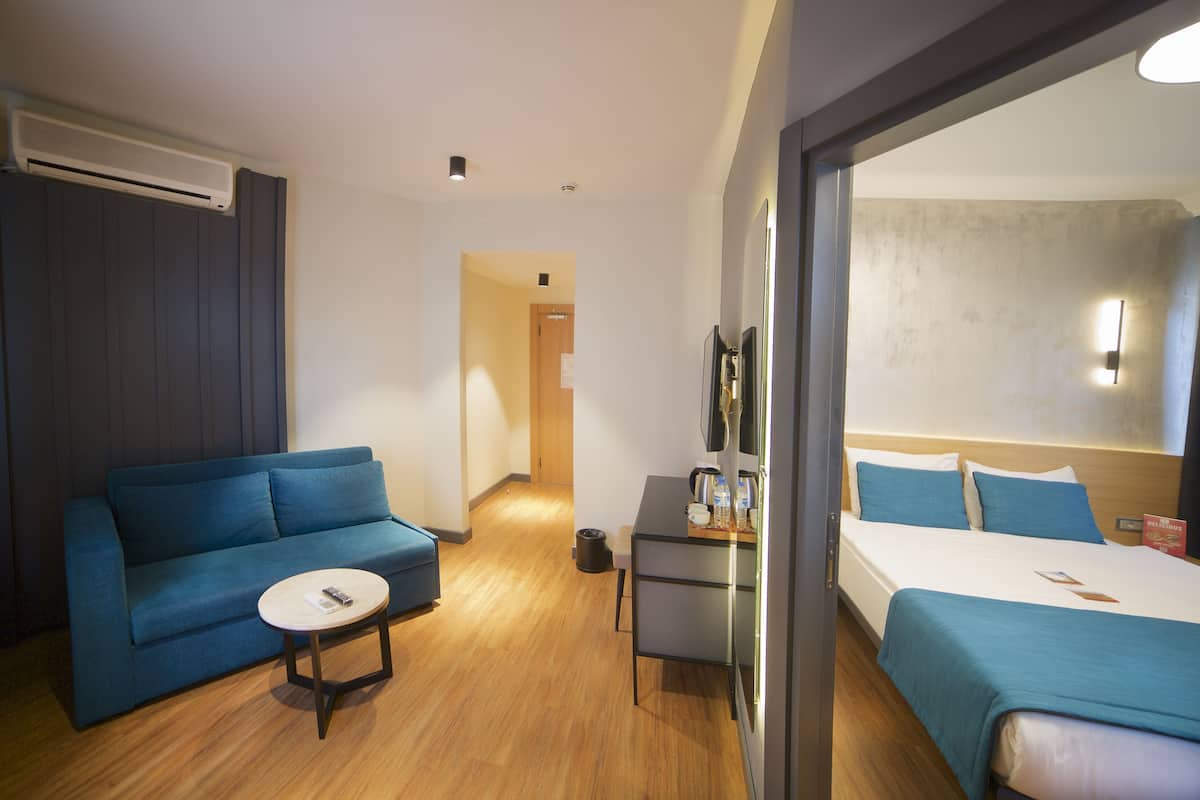 A hotel room with a bed, a sofa, a small table, and a desk.