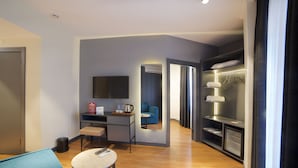 A modern hotel room with a desk, chair, and a small table. There is a sofa, a mirror, and a wardrobe with hanging clothes. - Barin Hotel (Istanbul)