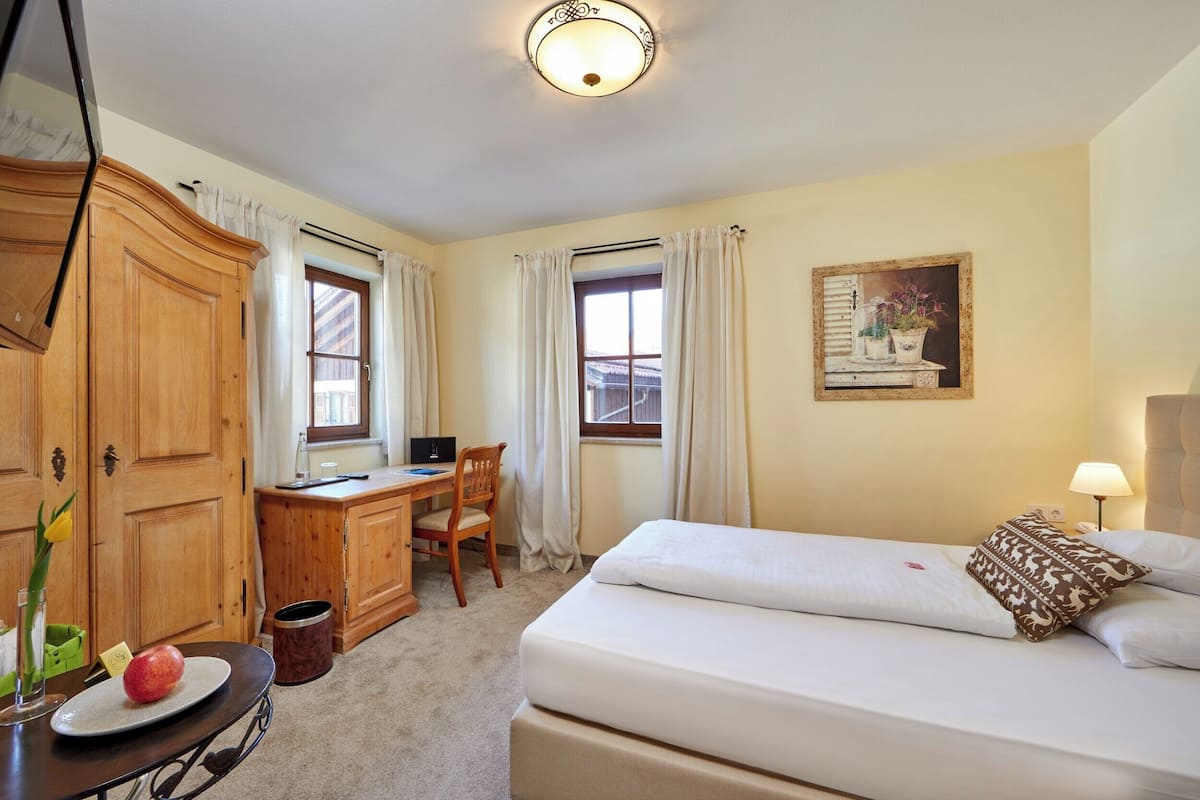 A hotel room with a bed, desk, chair, and wardrobe.