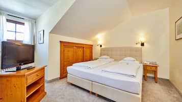 Quarto com duas camas, penteadeira de madeira, televisão e mesa de cabeceira.