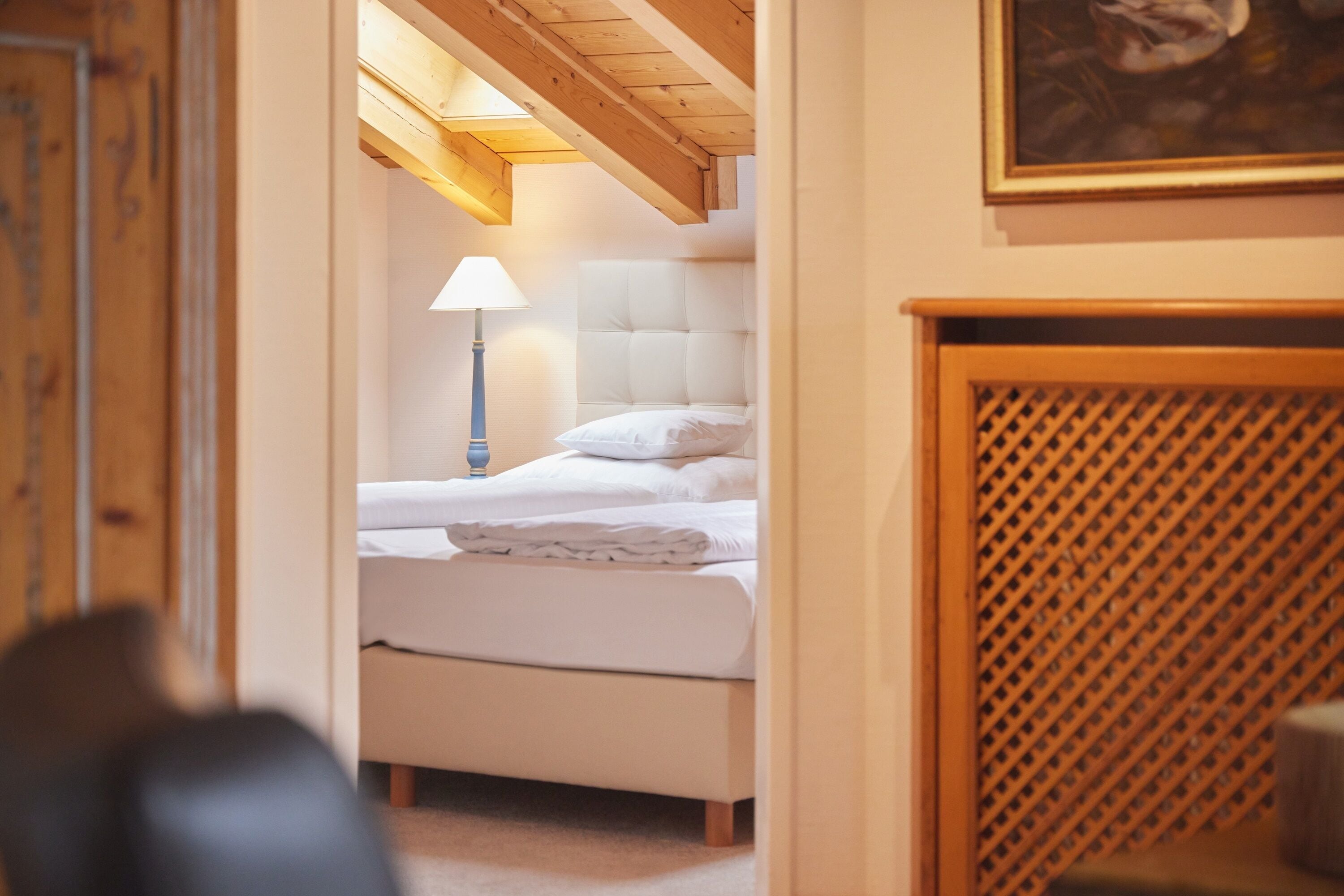 Un dormitorio con cama, mesita de noche, lámpara y cabecero de madera.