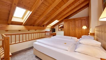 A bedroom with a wooden ceiling, a skylight, a bed with white linens, and wooden furniture.