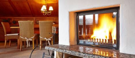 A cozy room with a fireplace, wooden chairs, and a dining table.