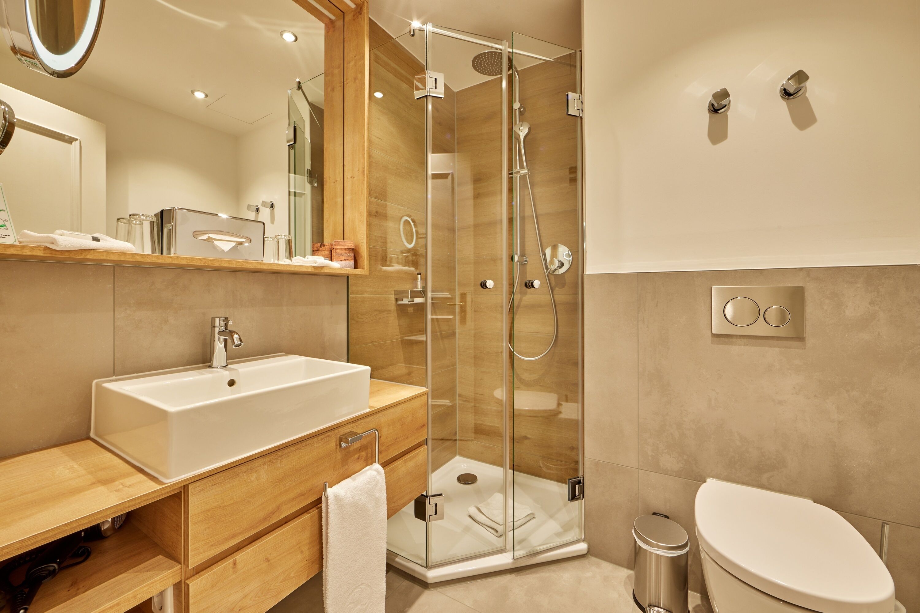 A modern bathroom with a glass-enclosed shower, a white sink, and a toilet.