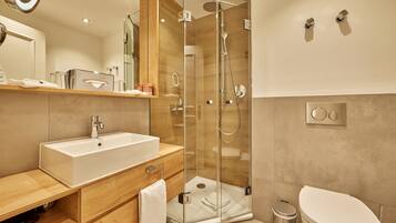 A modern bathroom with a glass-enclosed shower, a white sink, and a toilet.