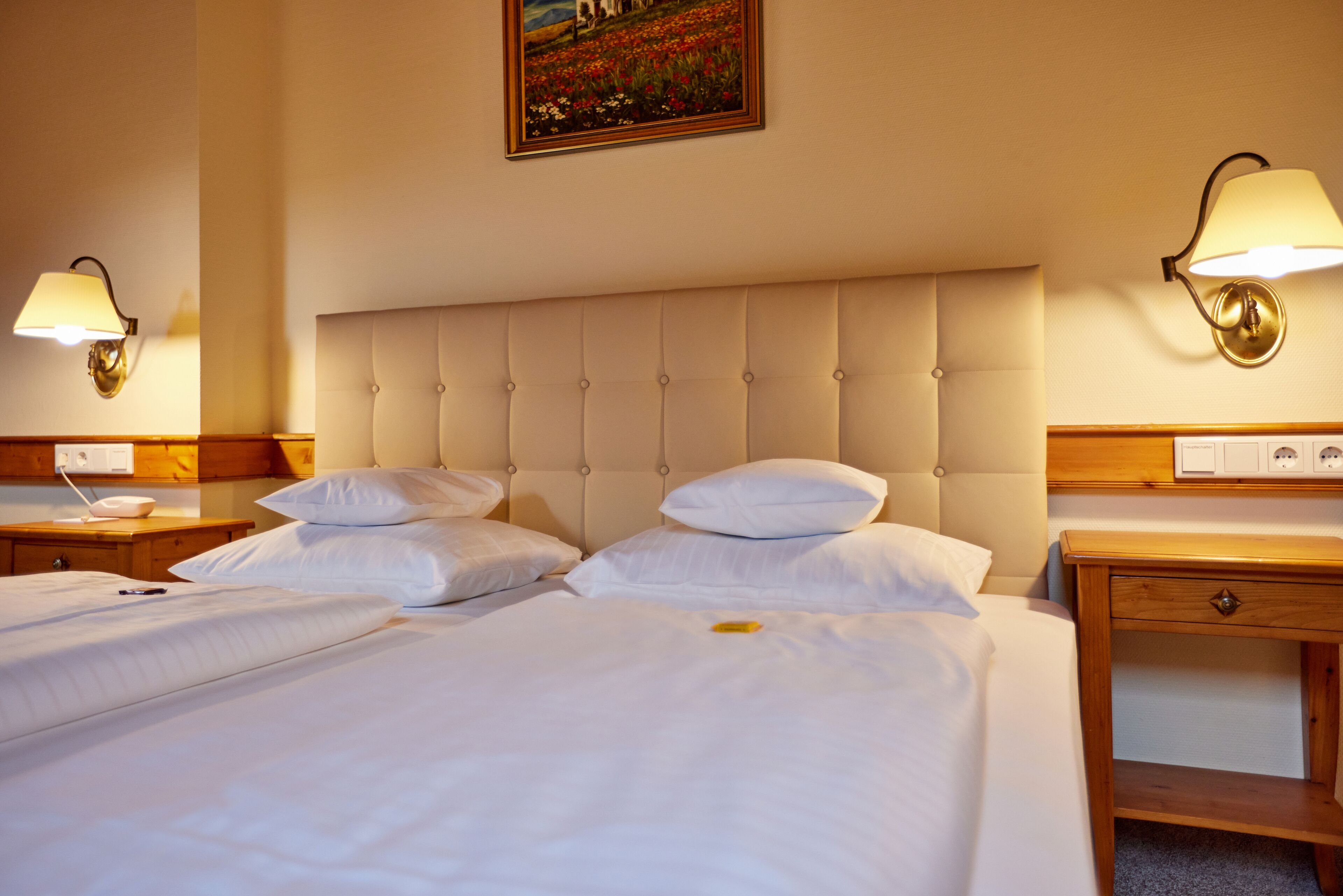Una habitación de hotel con una cama grande, dos mesitas de noche y una mesilla.