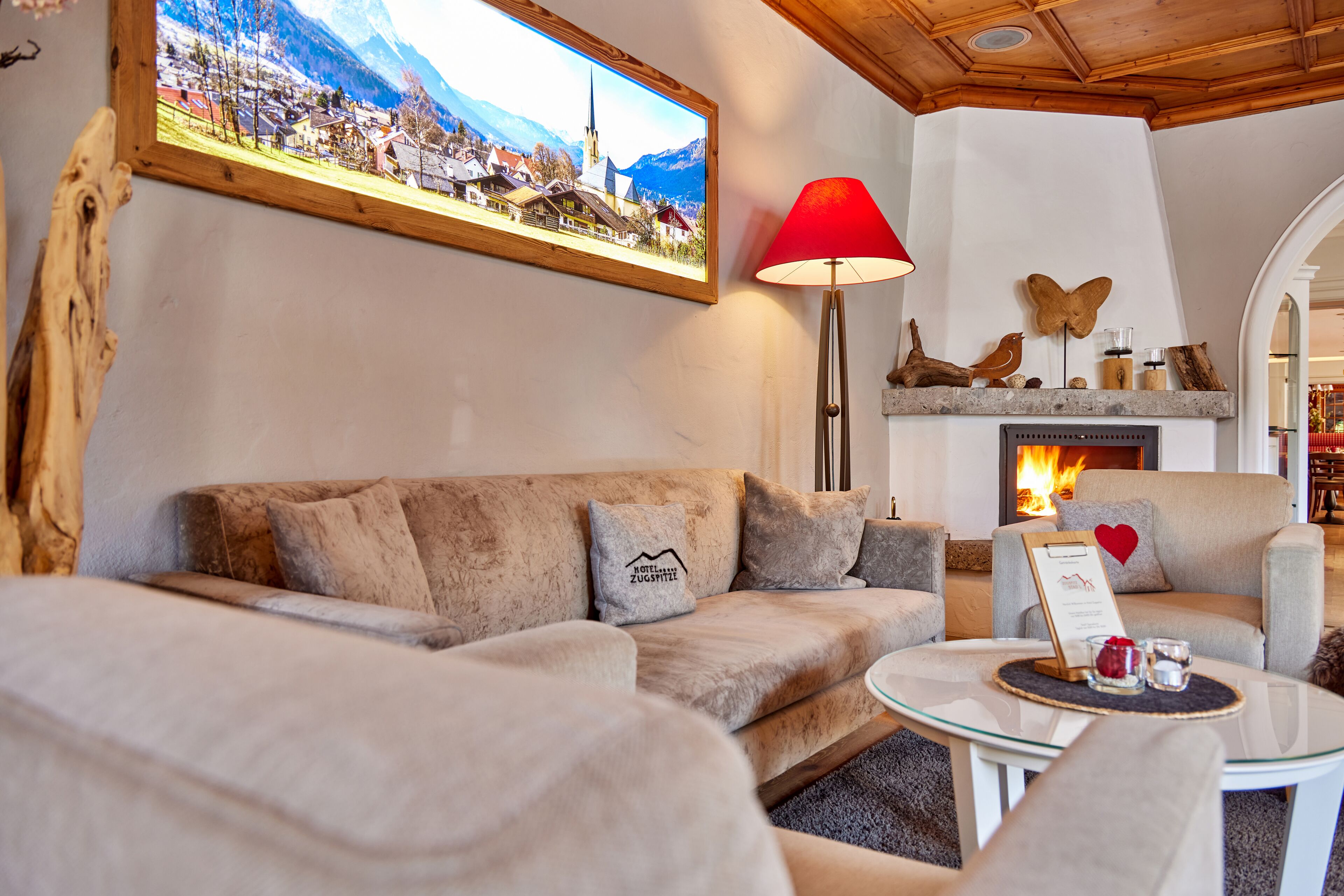 Una sala de estar acogedora con un sofá, sillones, una chimenea, una mesa con una lámpara y un cuadro en la pared.