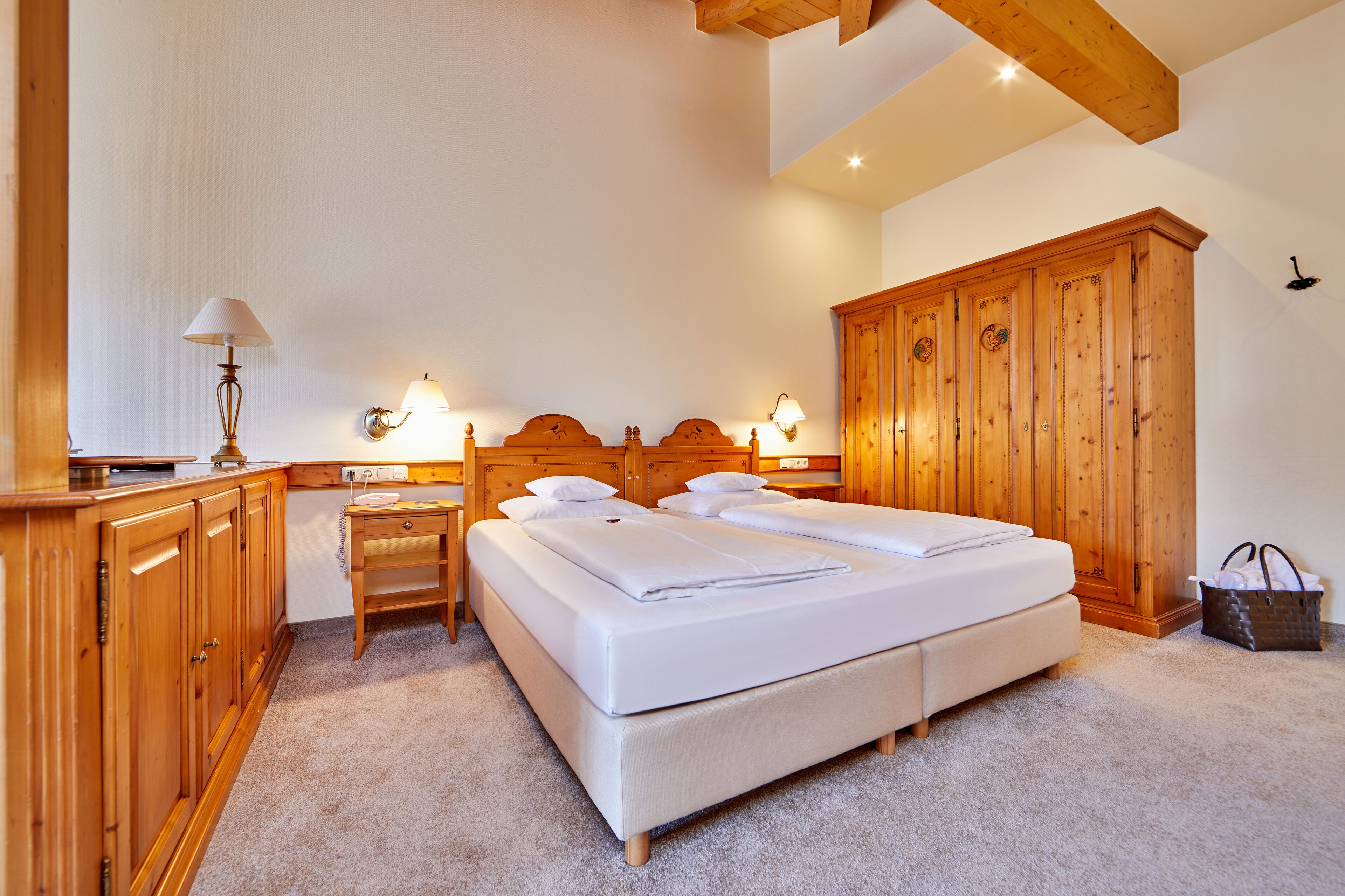 Un dormitorio con una cama grande, un armario de madera y un escritorio con lámpara.