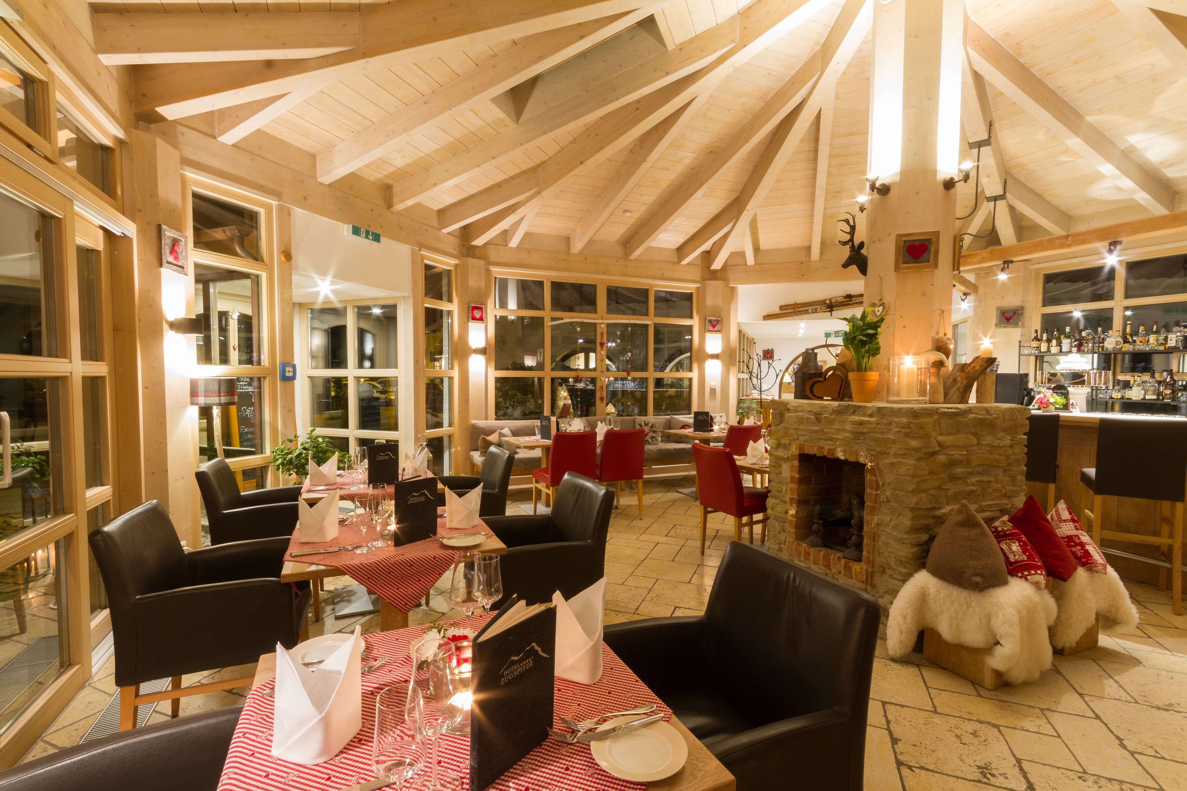 Ein gemütliches Restaurant mit Holzbalken, rot-weißen Karotischdecken und einem Steinkamin.