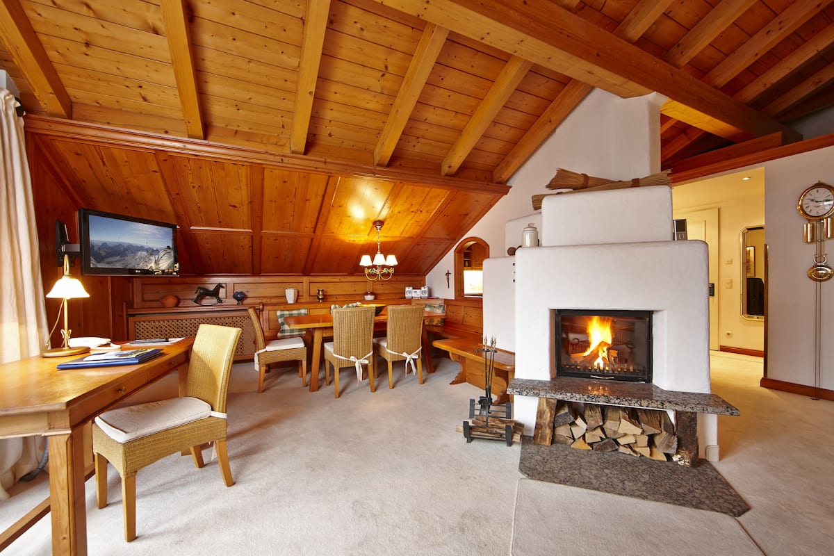 A cozy room with a fireplace, wooden furniture, a television, and a dining area.