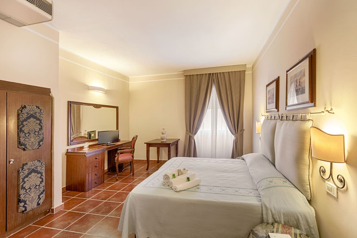 Una camera d'albergo con un letto, una scrivania, una sedia e una televisione.