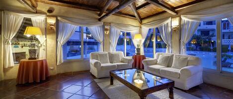 Una sala de estar acogedora con dos sofás blancos, una mesa de centro de vidrio y una chimenea.