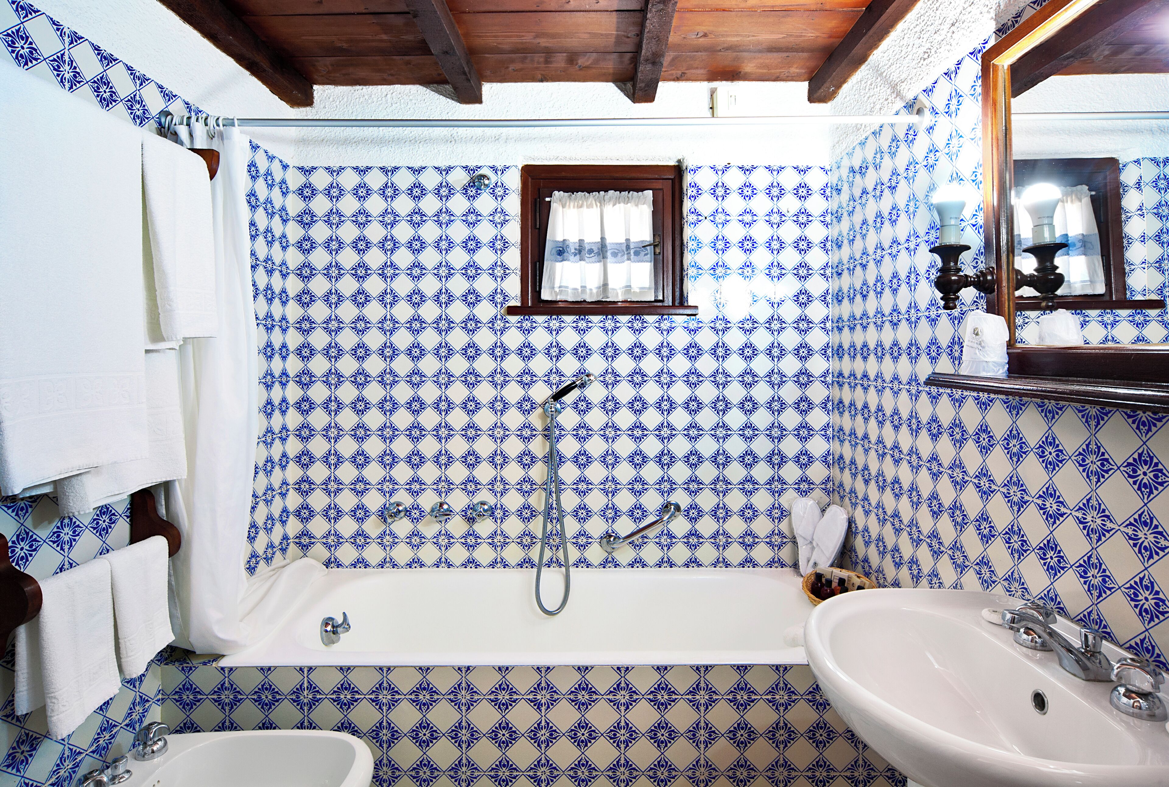 Un bagno con una vasca, un lavandino e una finestra con tenda.