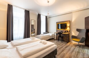 Habitación de hotel con dos camas, un escritorio, una silla, un televisor y un espejo.