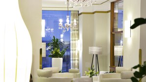 A well-lit room with a chandelier, a large window with curtains, and a floor lamp. - Hotel Wandl (Vienna)