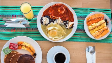 A breakfast setting with plates of food, a glass of orange juice, and a cup of coffee on a wooden table.