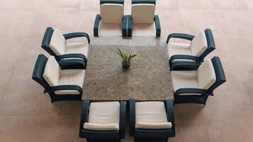A round table with eight chairs, a potted plant, and a tiled floor.