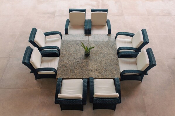 A round table with eight chairs, a potted plant, and a tiled floor.