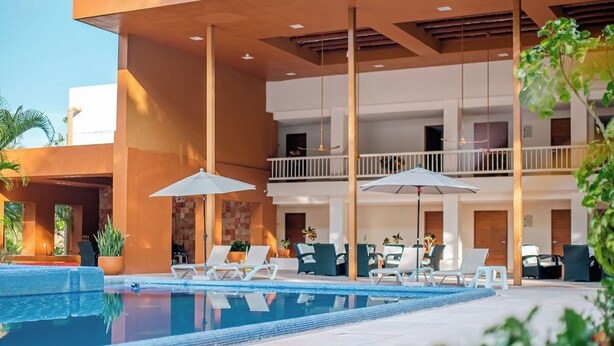A modern hotel with a pool area, outdoor seating, and a covered patio. - Hotel Ixzi Plus (Ixtapa)