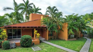 Una casa moderna con patio, rodeada de exuberante vegetación y palmeras.