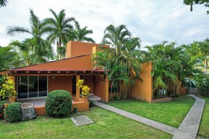 Una casa moderna con patio, rodeada de exuberante vegetación y palmeras.