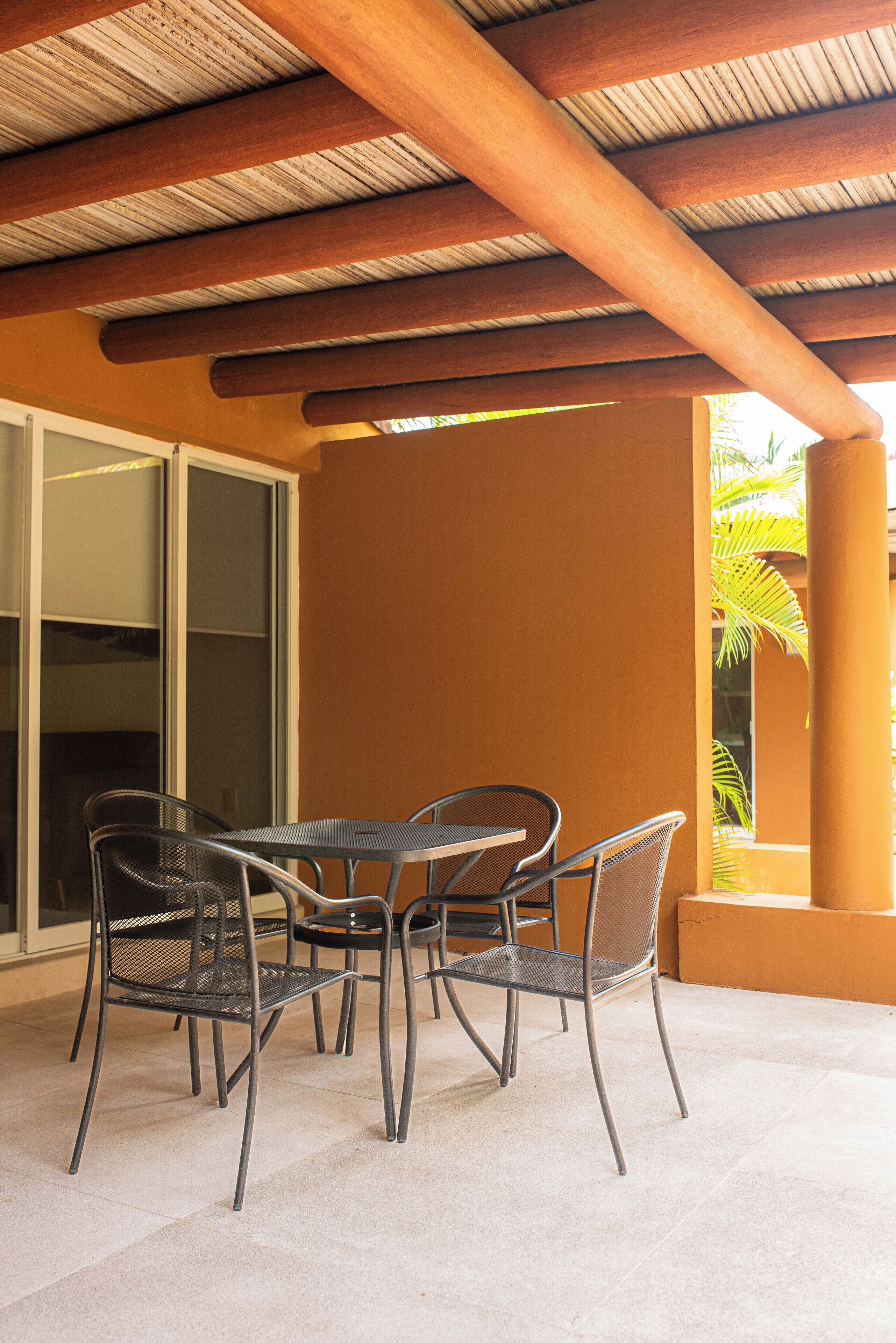 An outdoor patio with a table and chairs, a sliding glass door, and a palm tree in the background.