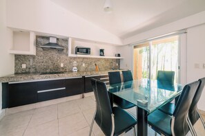 A modern kitchen with granite countertops, black cabinets, and a glass dining table with chairs. - Hotel Ixzi Plus (Ixtapa)