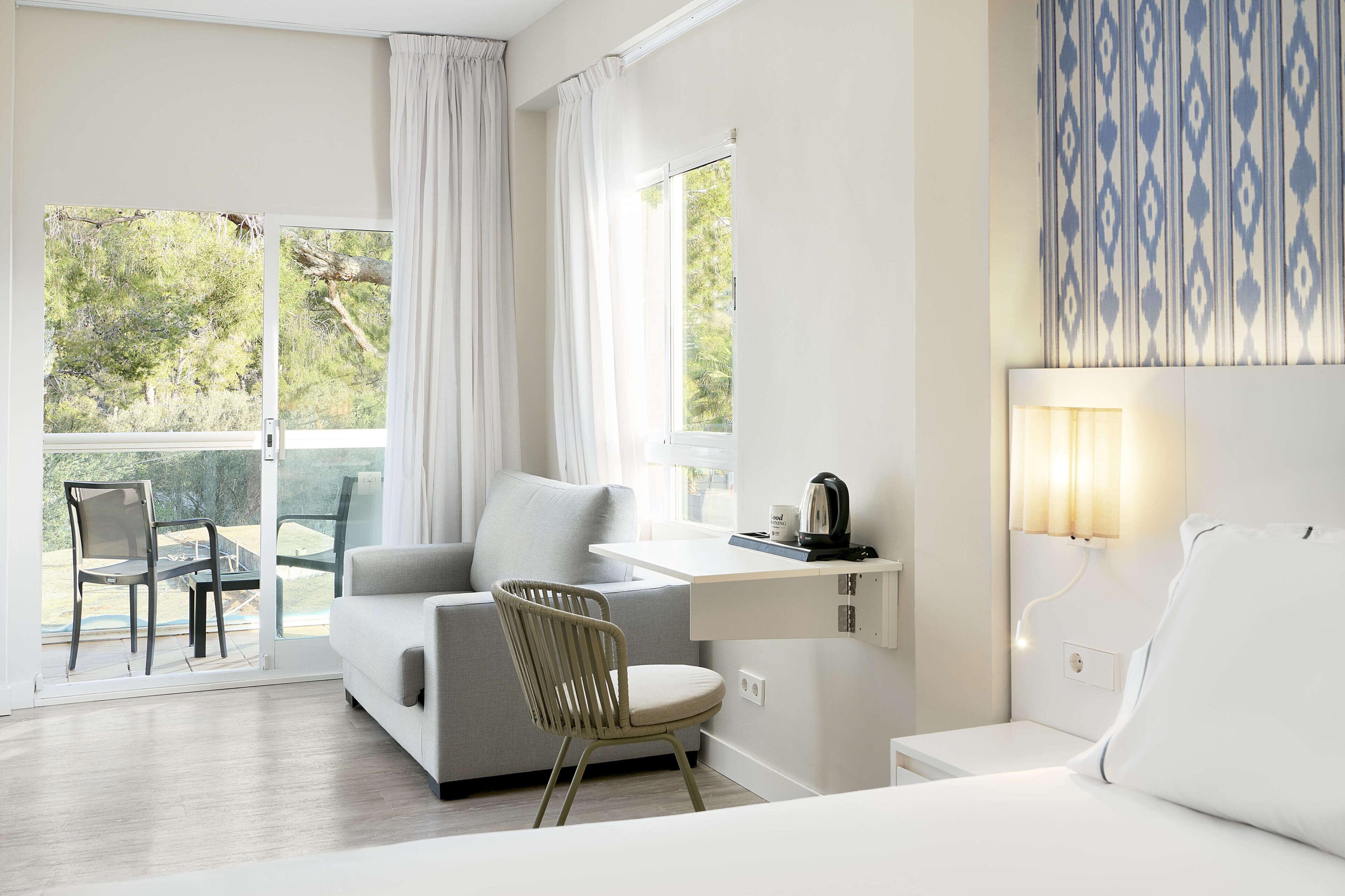 Ein modernes Hotelzimmer mit einer Couch, einem Sessel, einem Schreibtisch und einem Bett.