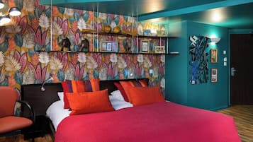 A bedroom with a bed, a chair, a wall with a leaf pattern, and shelves with various items.