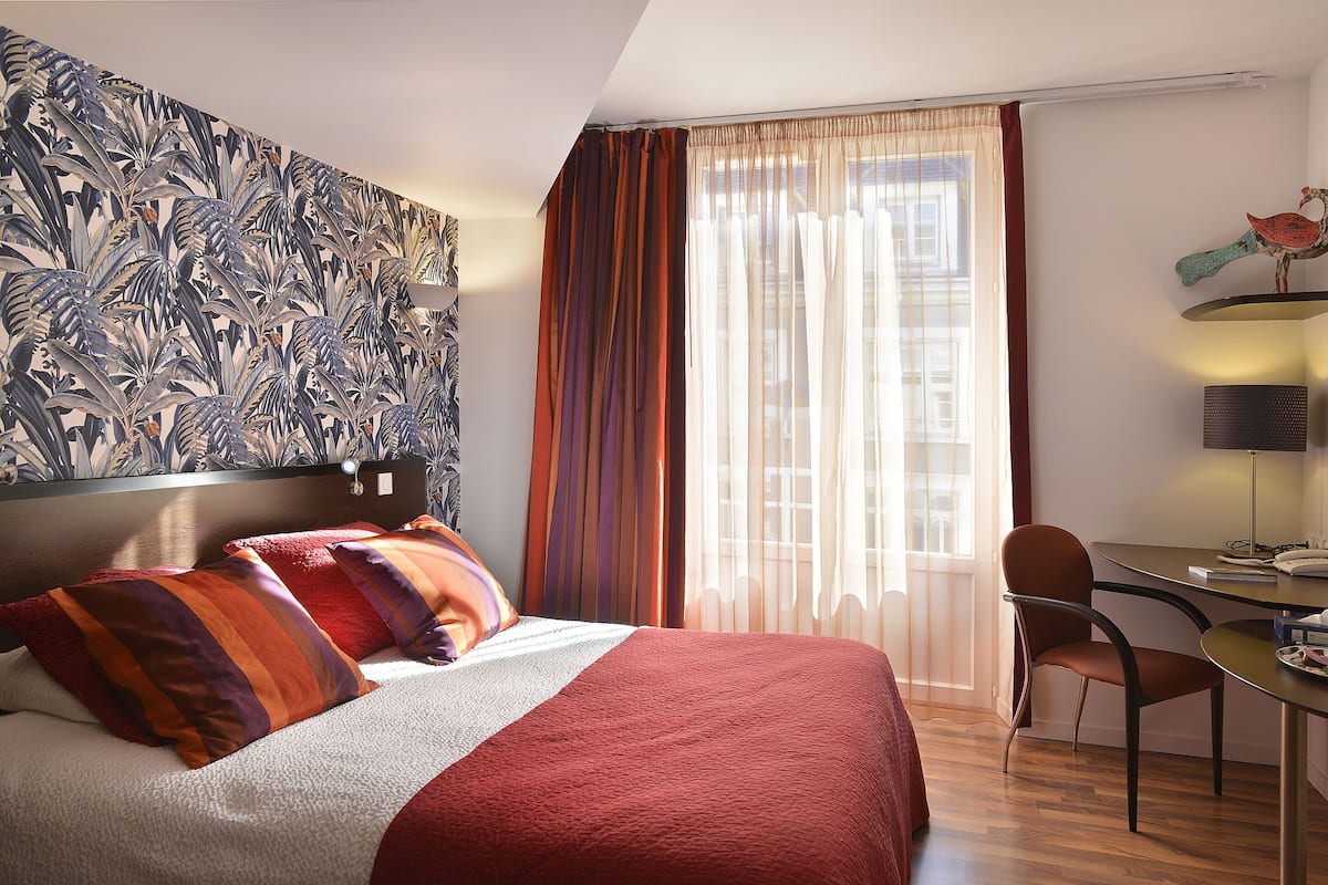 A hotel room with a bed, a desk, and a chair.