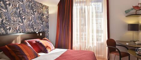 A hotel room with a bed, a desk, and a chair.