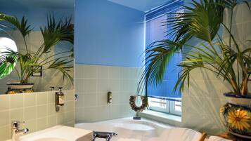Une salle de bain avec une baignoire, un lavabo et deux plantes en pot.