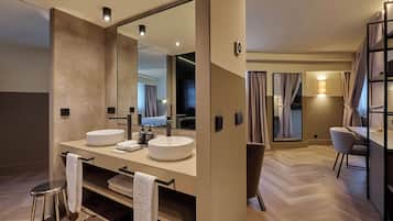 A modern hotel bathroom with two sinks, a large mirror, and a vanity with towels.