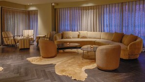 Una sala de estar moderna con un sofá grande, sillones, una mesa de centro y una alfombra.