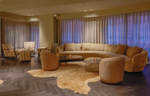 A modern living room with a large sofa, armchairs, a coffee table, and a rug.