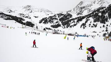 Ein verschneiter Skipisten mit Skifahrern und Snowboardern.