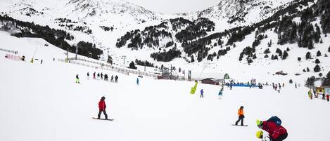 Pista de esquí nevada con esquiadores y snowboarders.
