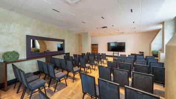 A conference room with rows of chairs, a large flat-screen TV, and a wooden reception desk.