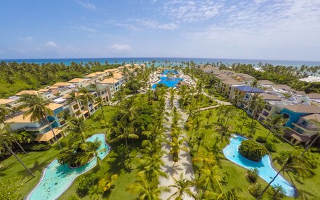 A resort with multiple swimming pools, palm trees, and beachfront views.