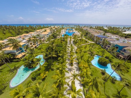 A resort with multiple swimming pools, palm trees, and beachfront views.