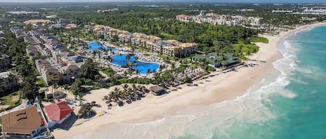 A resort with multiple buildings, a beach, and a large swimming pool.