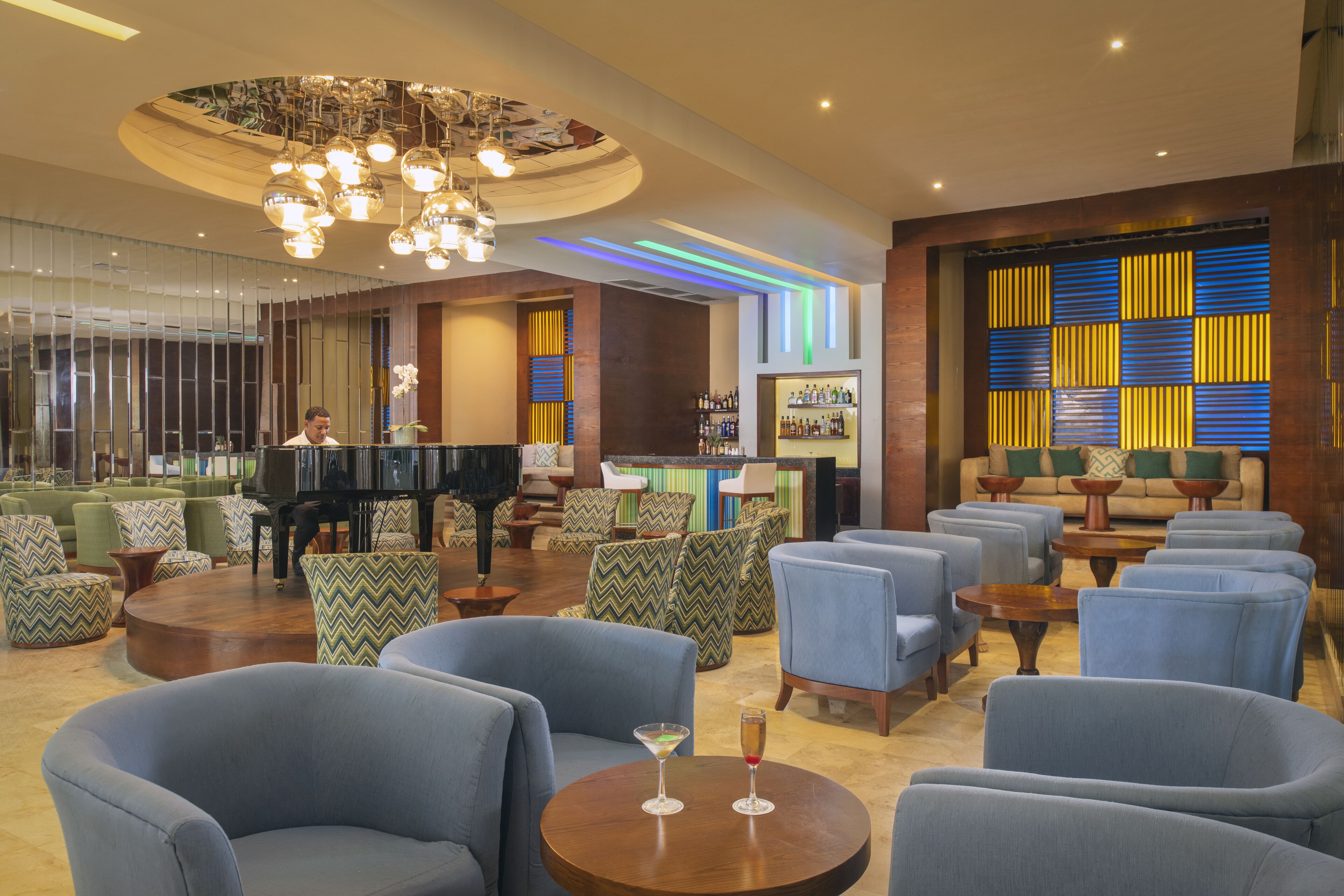 Een ruime lobby met een vleugelpiano, comfortabele zithoeken en een bar.