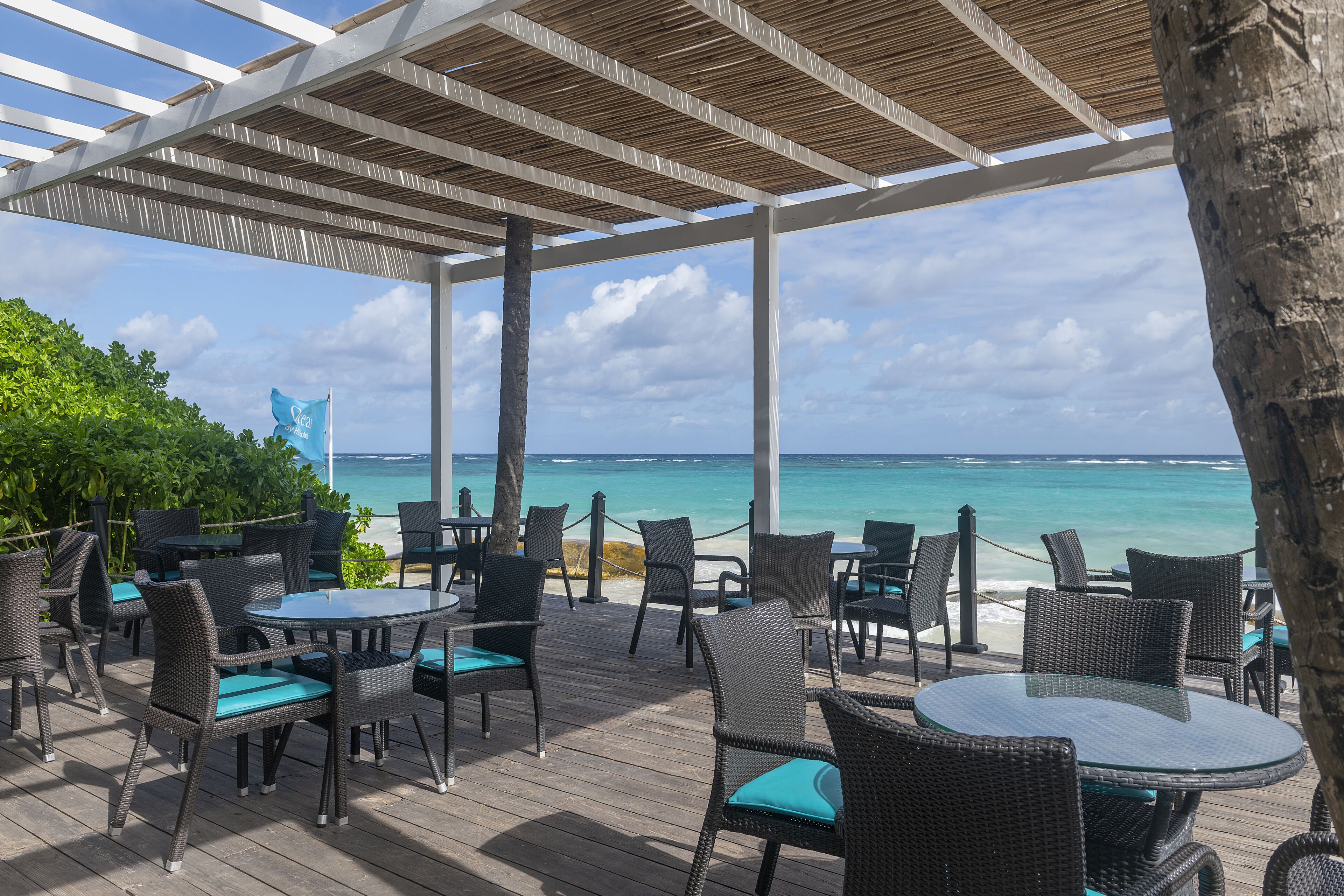 Une terrasse extérieure aménagée avec des meubles en osier et offrant une vue sur l’océan.