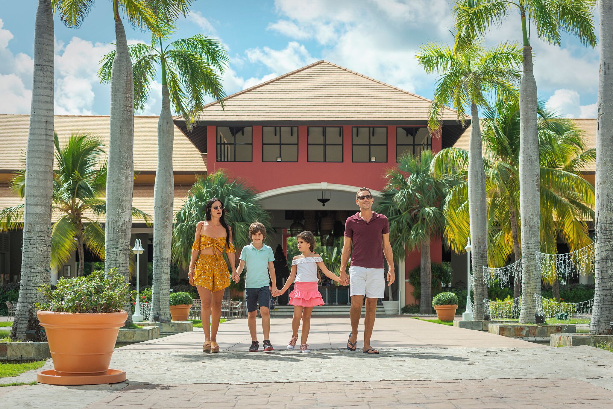 A family walking in front of a building with a red roof and multiple windows.