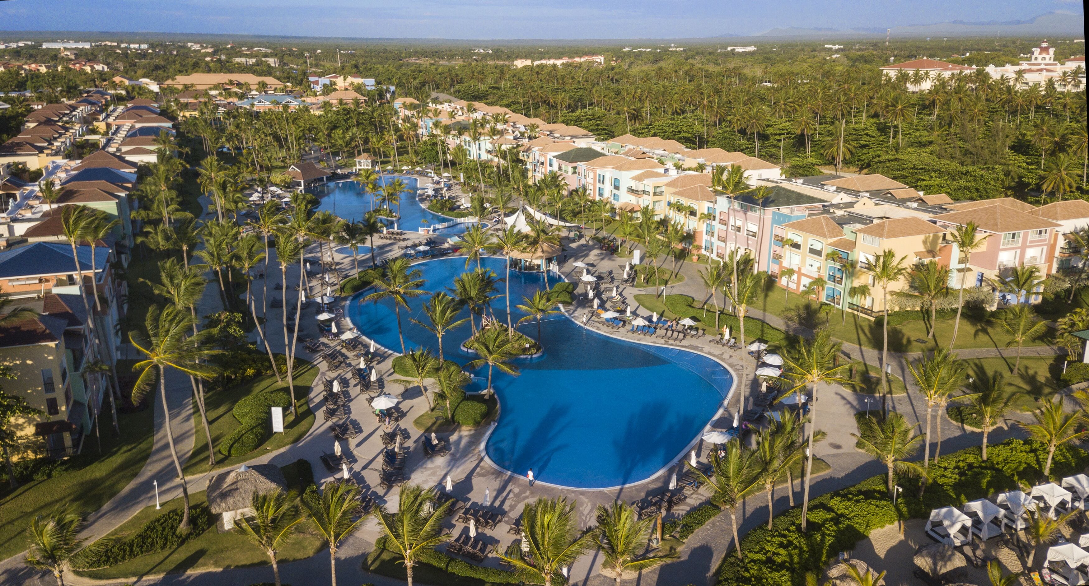 Un complexe hôtelier doté de plusieurs piscines, de palmiers et présentant une variété de styles architecturaux.