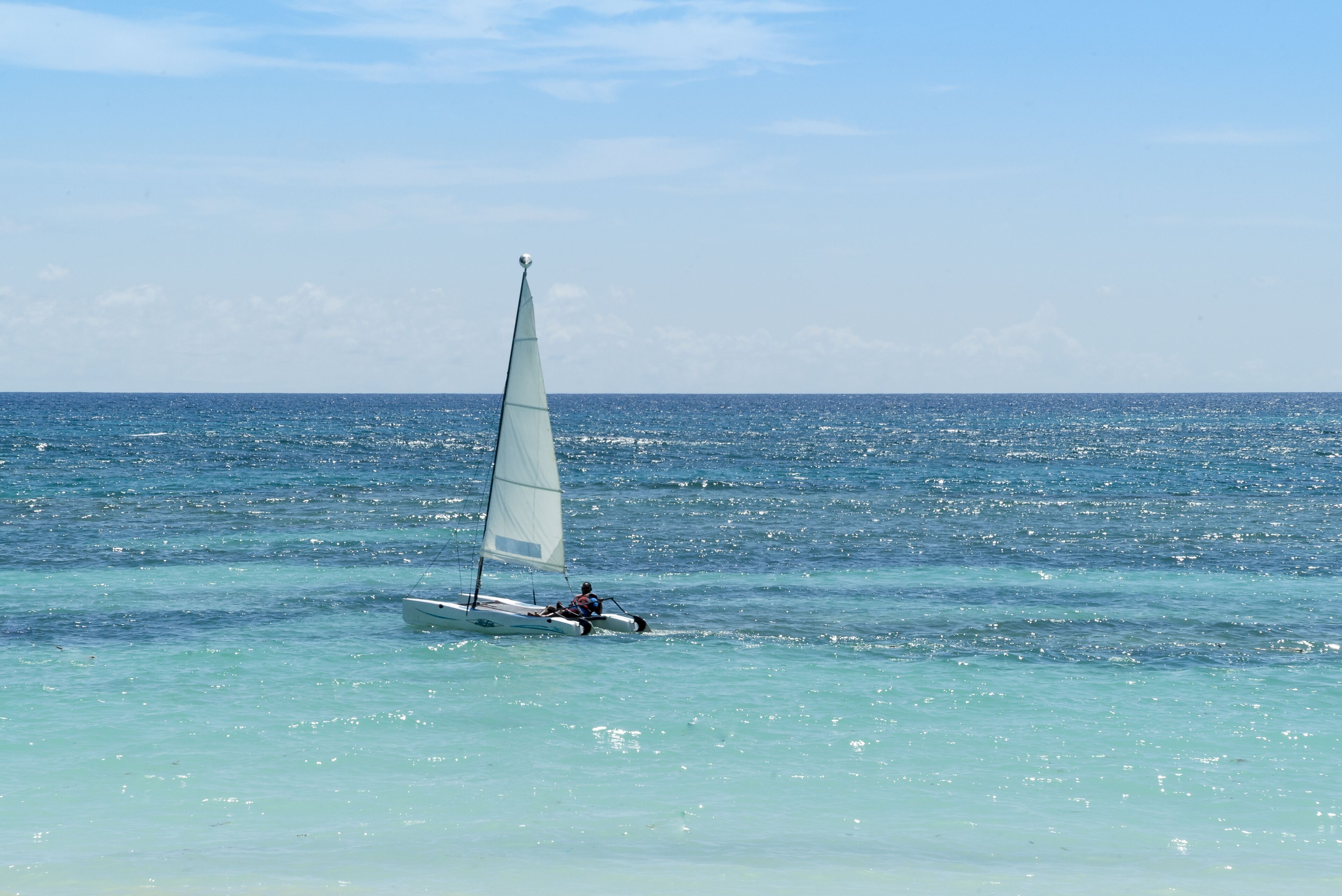 A sailboat on a calm sea with clear skies.