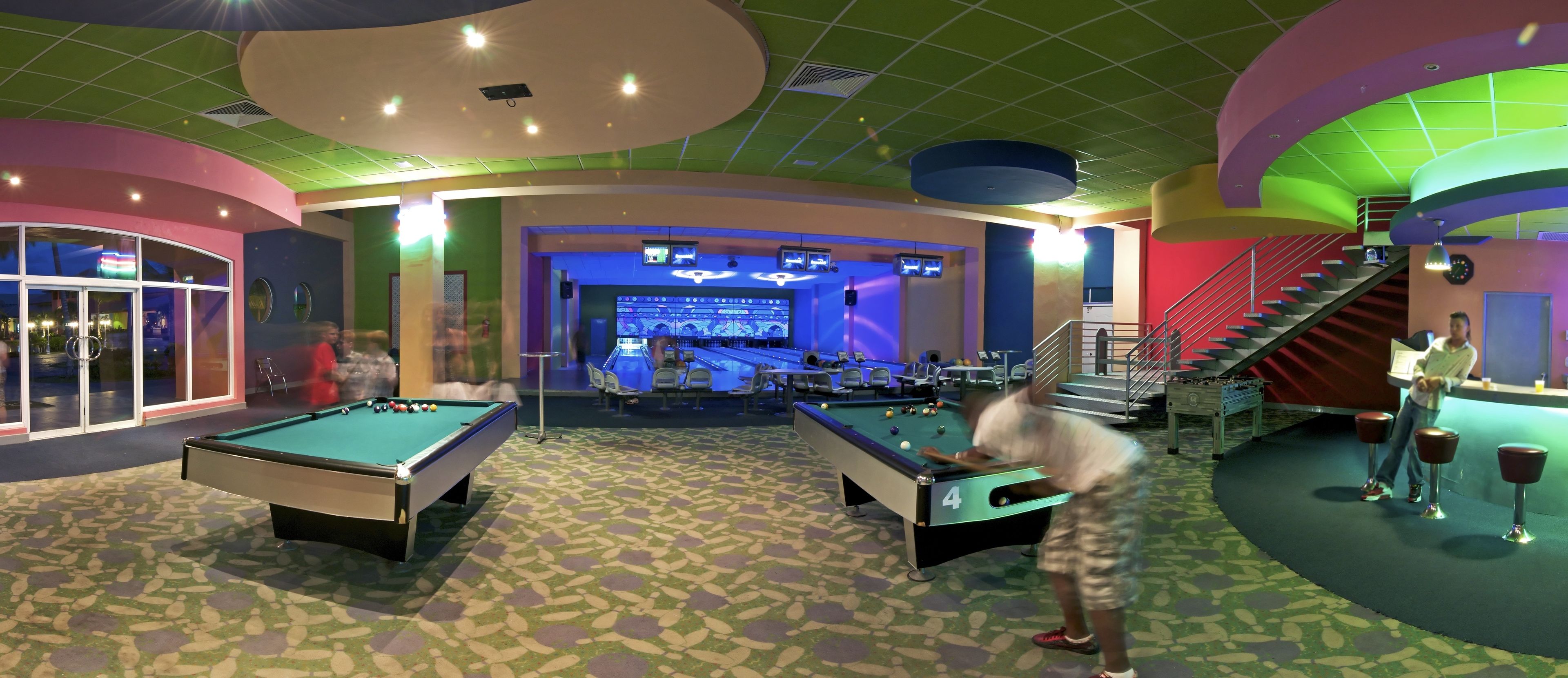 A pool table with balls, a billiards table, and a bar area with stools and a counter.